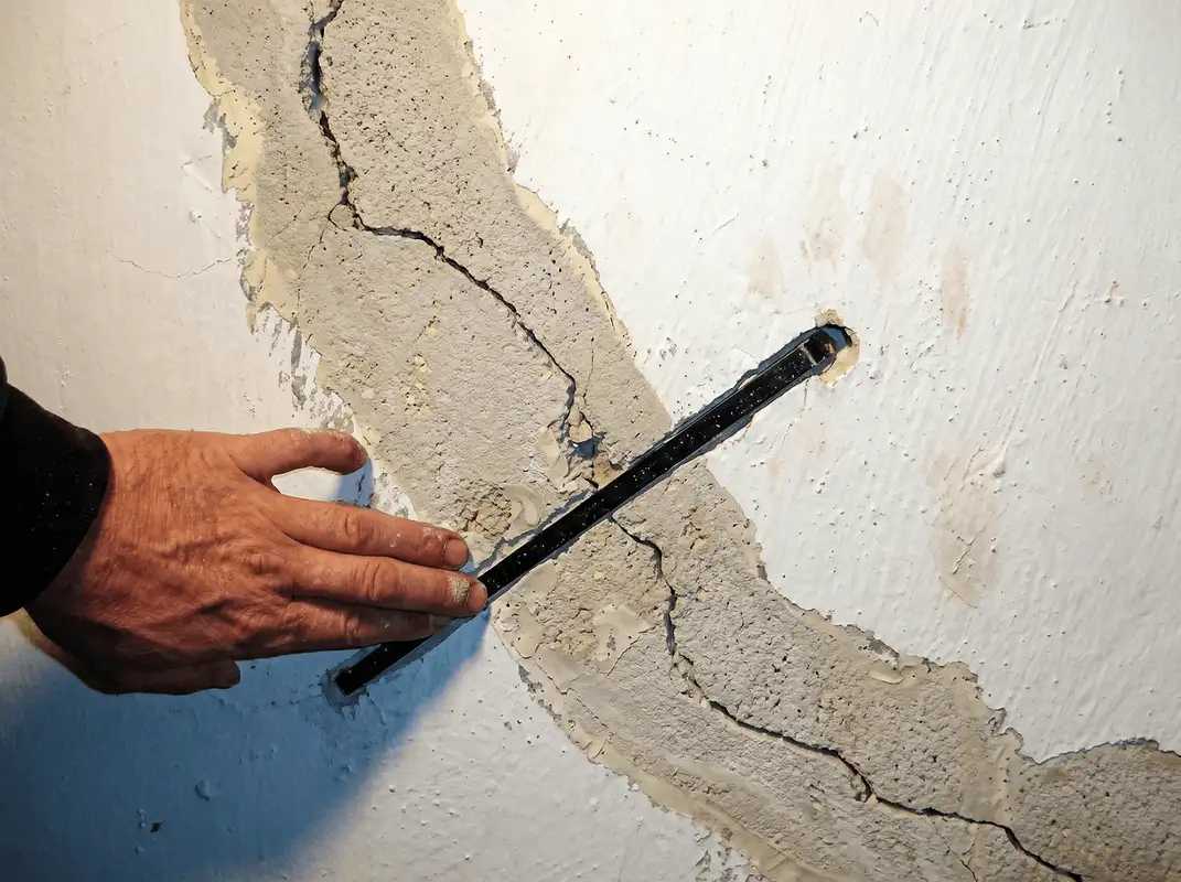 A wall with a large crack is being inspected by a professional in Allentown, PA