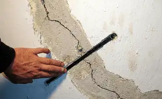 A wall with a large crack is being inspected by a professional in Allentown, PA
